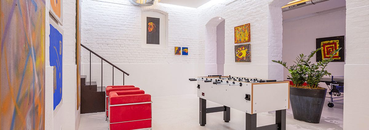 Clubzimmer mit roten Sesseln und Kicker