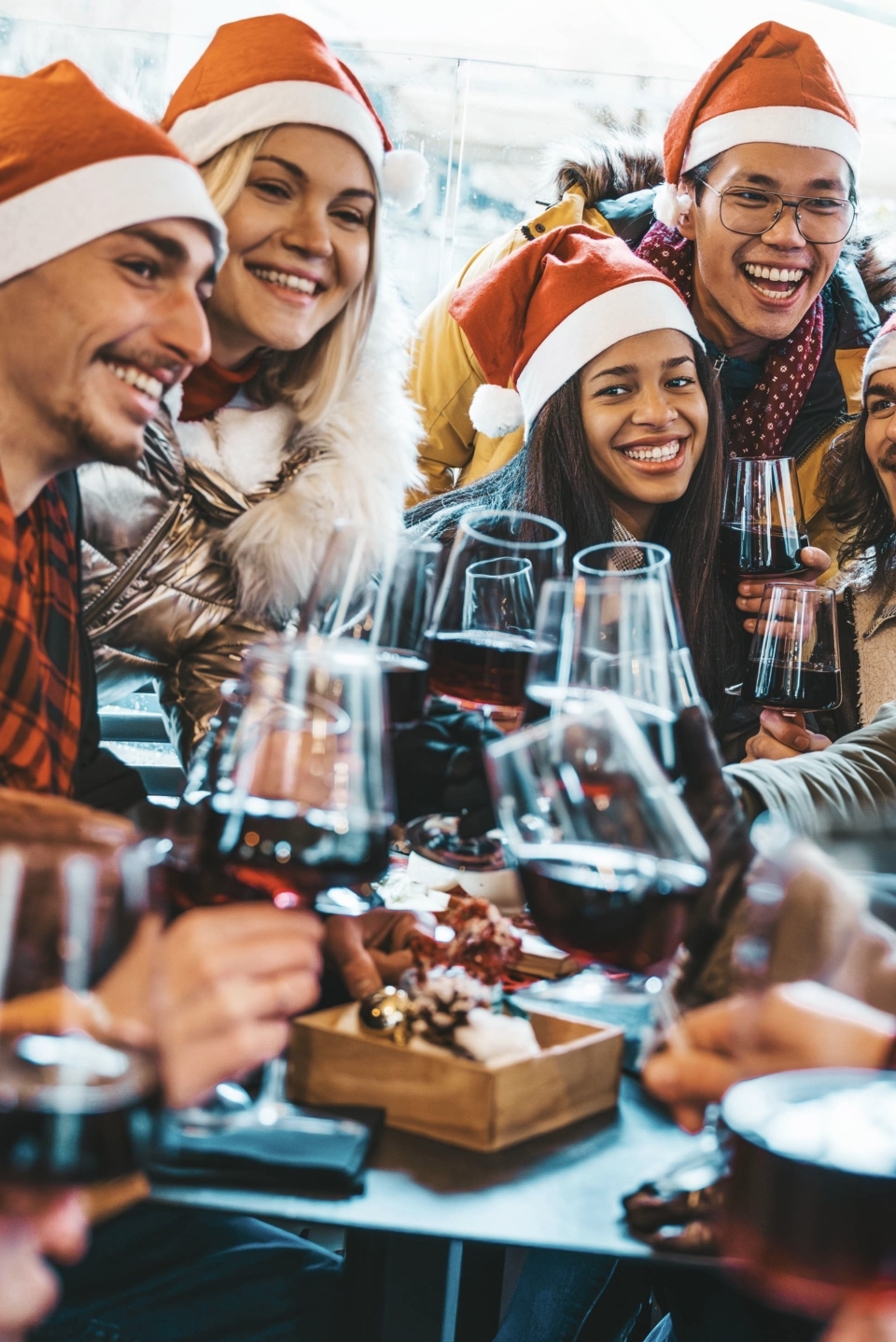 christmas-party fröhliche menschen mit weihnachtsmützen stoßen zusammen mit wein an